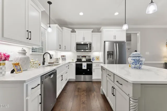 a kitchen with stainless steel appliances granite countertop a refrigerator a sink dishwasher a stove and white cabinets with wooden floor