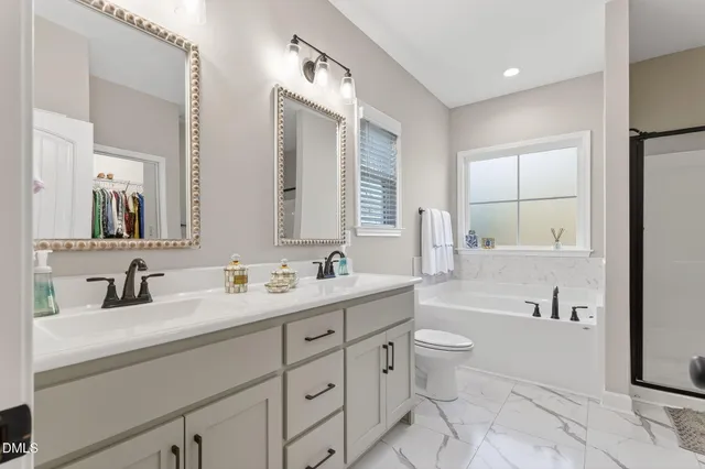 a bathroom with a double vanity sink toilet mirror and bathtub