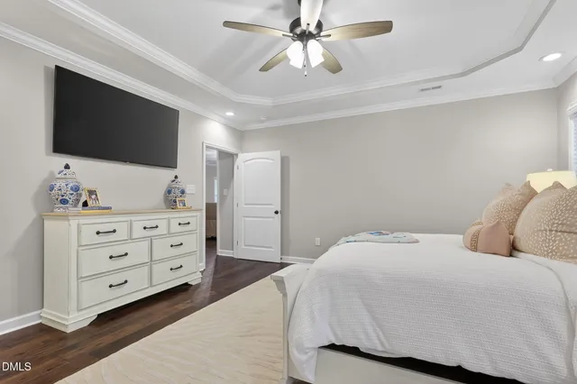 a bedroom with a bed a flat screen tv and a chandelier