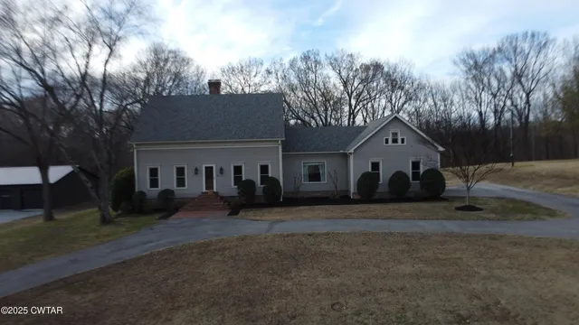 a front view of house with yard and trees in the background
