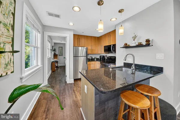 a kitchen with stainless steel appliances granite countertop a sink and a refrigerator