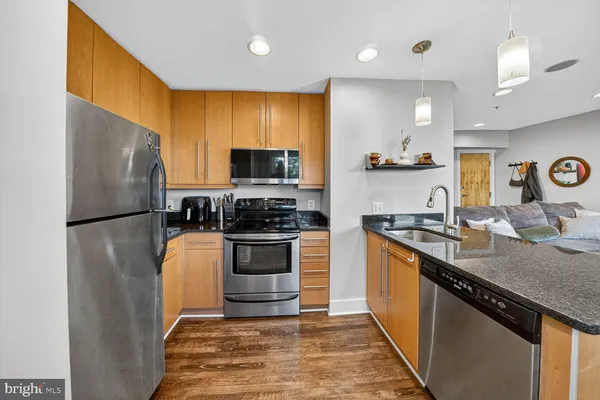 a kitchen with stainless steel appliances granite countertop a sink stove refrigerator and cabinets