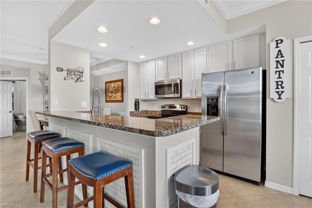 a kitchen with stainless steel appliances granite countertop a refrigerator a sink a stove a dining table and chairs