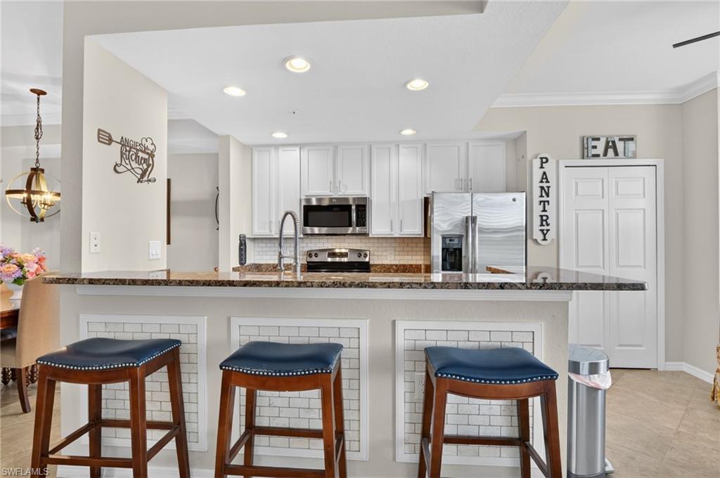 9513 Avellino Way, Unit 2014 Naples, FL 34113 - Photo 23 of 41 a kitchen with stainless steel appliances granite countertop a stove top oven a sink and cabinets
