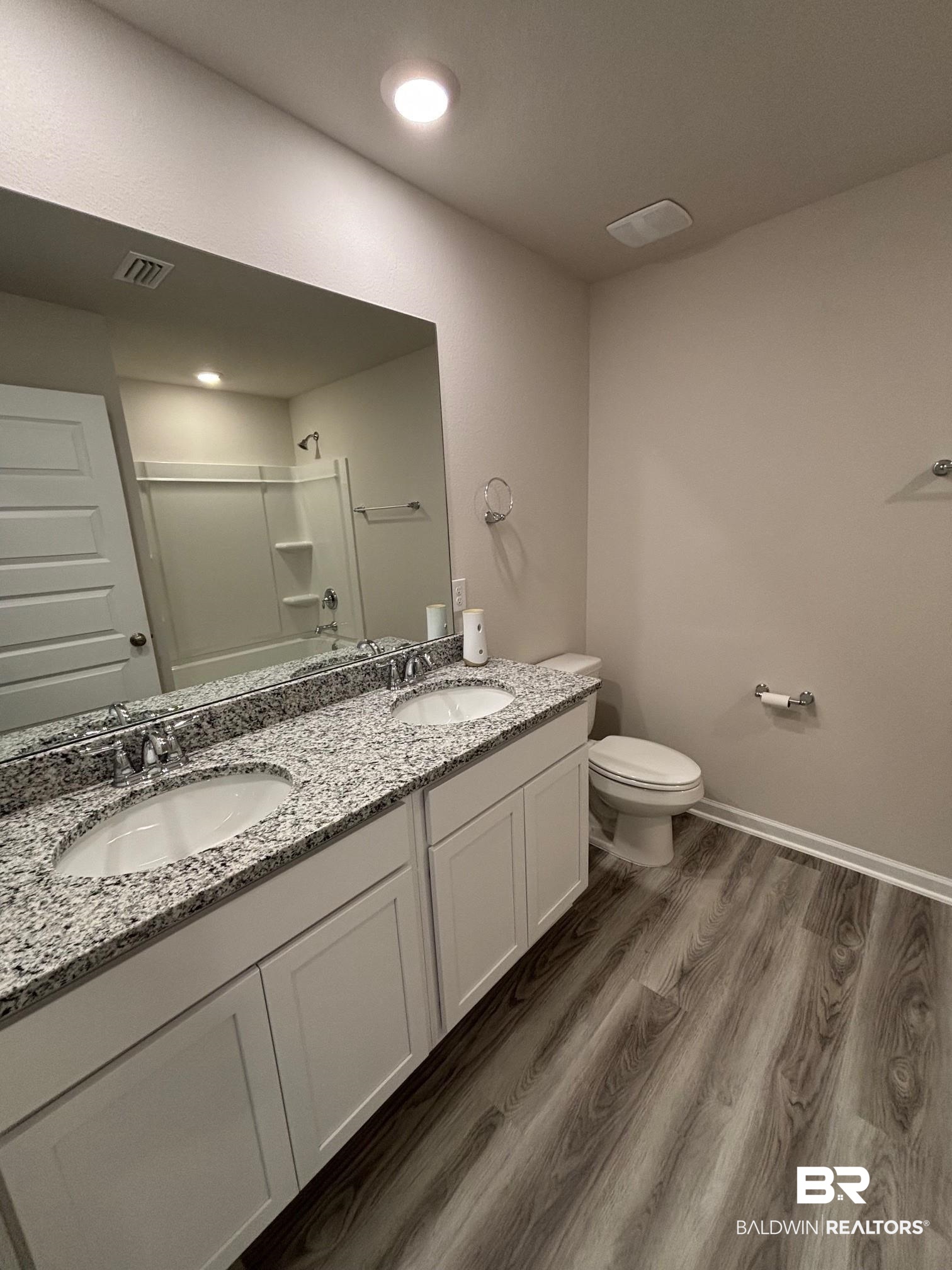 22215 Aleutian Avenue Foley, AL 36535 - Photo 13 of 34 Bathroom featuring wood-type flooring, vanity, toilet, and a shower with shower door
