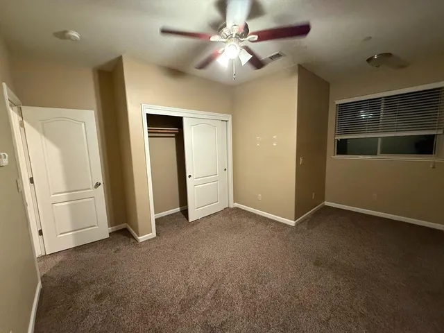 a view of an empty room with a chandelier fan