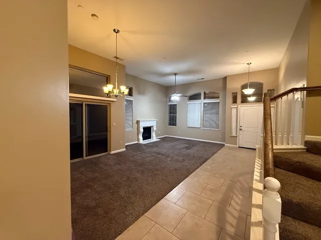 a view of a livingroom with furniture chandelier fan and kitchen view