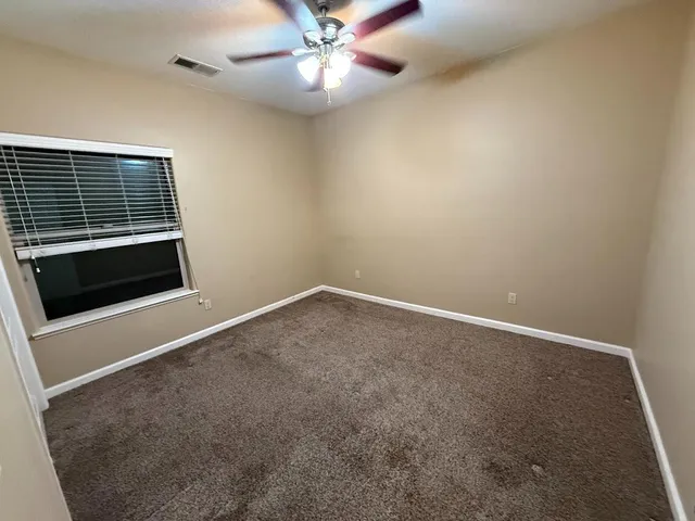 an empty room with windows and fan