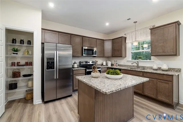 a kitchen with granite countertop stainless steel appliances a refrigerator a stove a sink a center island and cabinets