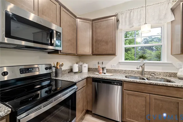 a kitchen with stainless steel appliances a sink a stove a microwave cabinets and a window