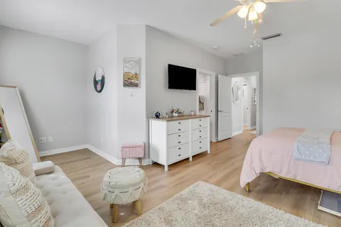 a spacious bedroom with a bed and a flat tv screen on the dresser