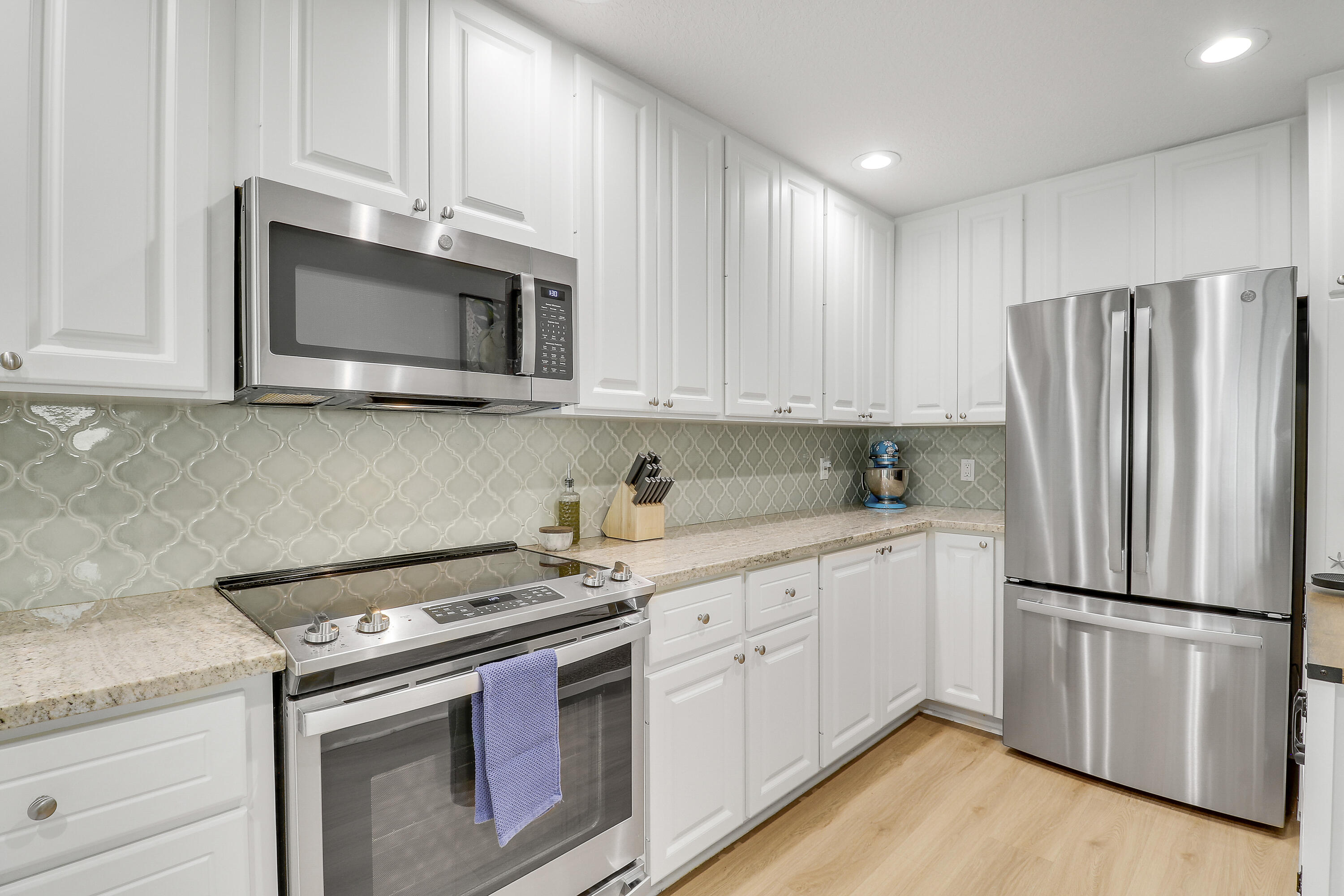 151 Rivinia Drive Jupiter, FL 33458 - Photo 7 of 40 a kitchen with stainless steel appliances granite countertop a stove a refrigerator and a microwave