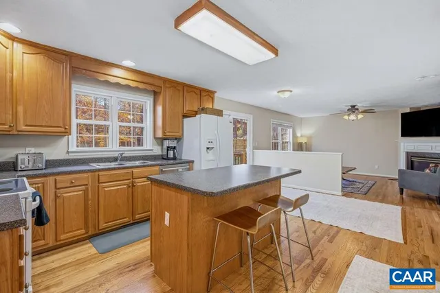 a kitchen with stainless steel appliances granite countertop a table chairs sink and wooden cabinets