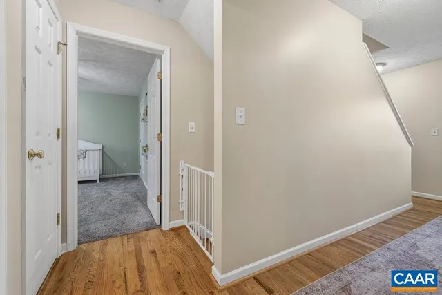 a view of a hallway with wooden floor and a bathroom