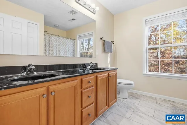 a spacious bathroom with a granite countertop sink a toilet a mirror and a window