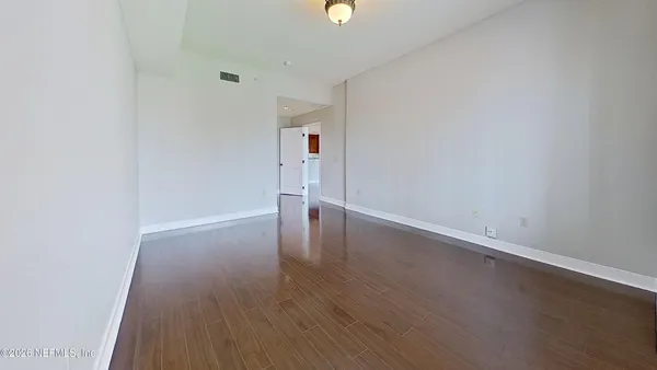 an empty room with wooden floor and windows