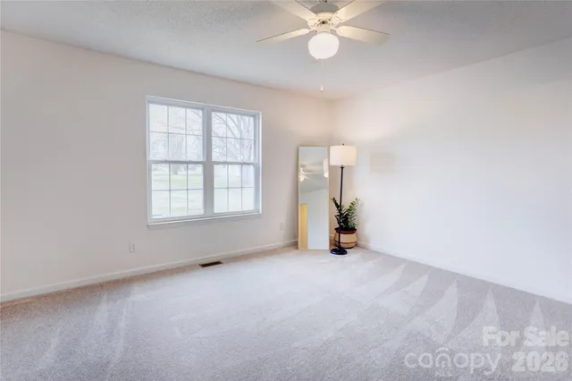 an empty room with windows and fan