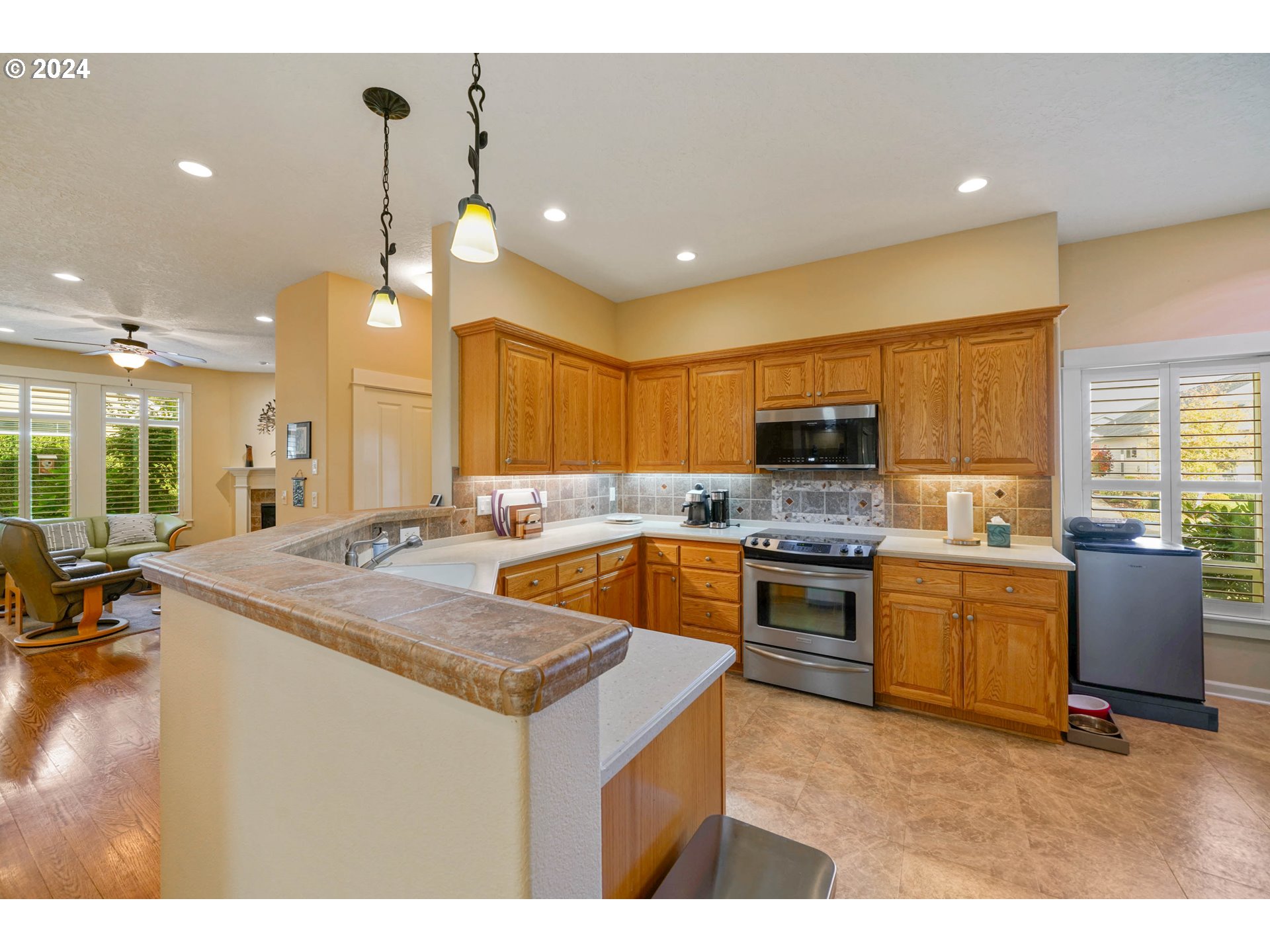 2155 Southeast Rhododendron Avenue Dallas, OR 97338 - Photo 17 of 40 a kitchen with a stove a sink a kitchen island with chairs and wooden cabinets