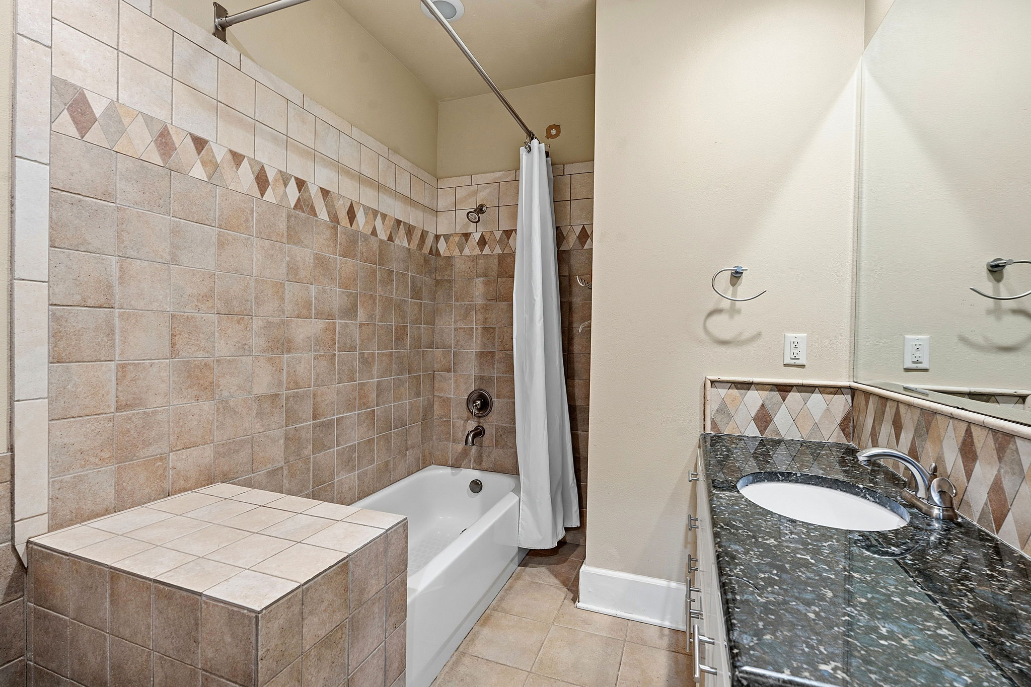 1305 Cometa Street Austin, TX 78721 - Photo 18 of 28 A well-appointed bathroom features a tub-shower combination, a tiled surround, and a granite-topped vanity.