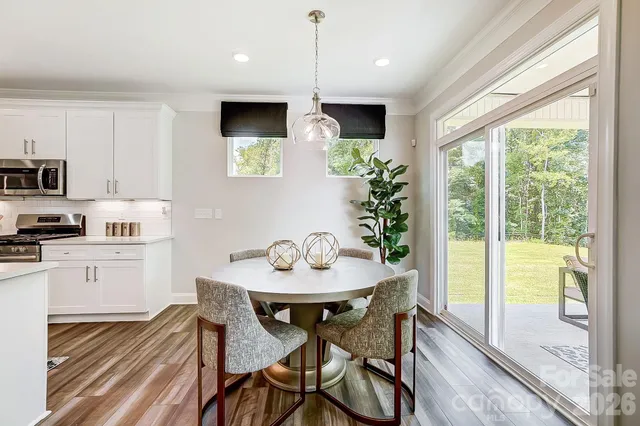 a kitchen with stainless steel appliances granite countertop sink stove and white cabinets with wooden floor