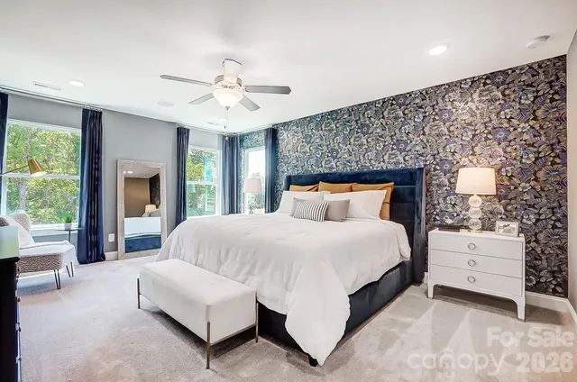 a spacious bedroom with a large bed and a chandelier fan