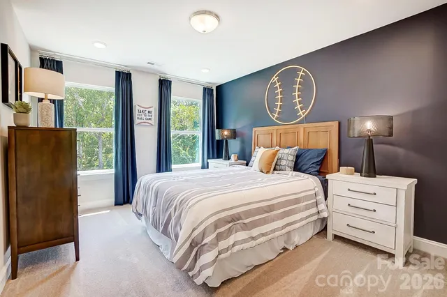 a bedroom with a bed a mirror on dresser and a large window