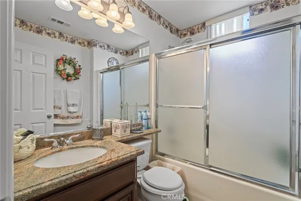 a bathroom with a granite countertop sink mirror vanity and toilet