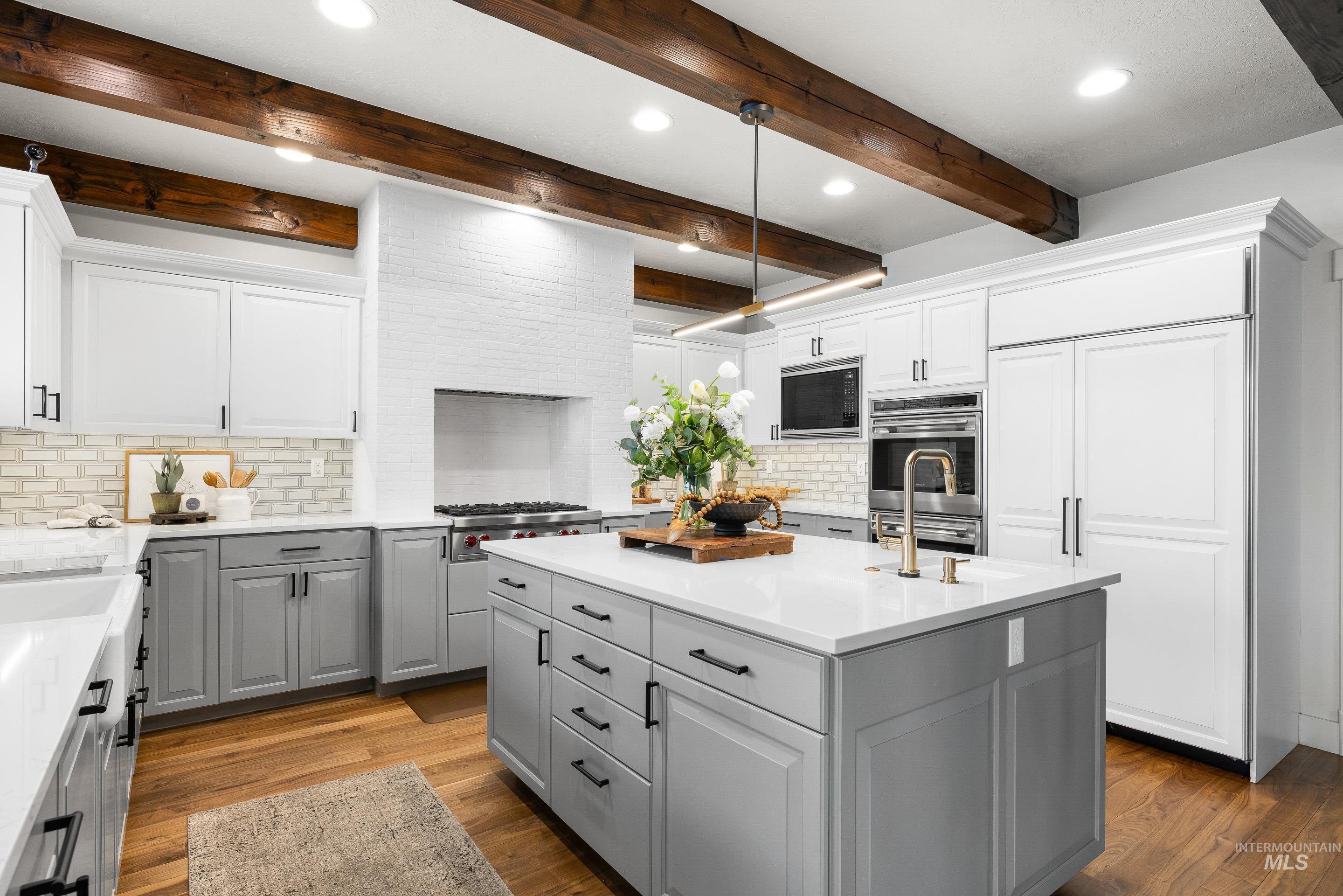 1166 East Rivers End Drive Eagle, ID 83616 - Photo 13 of 50 Kitchen featuring decorative backsplash, an island with sink, dual tone cabinets, dark wood-style flooring, and built in appliances