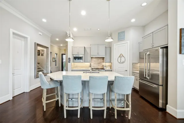 a kitchen with stainless steel appliances kitchen island granite countertop a dining table chairs refrigerator and microwave