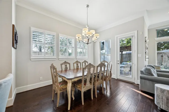 a dining room with wooden floor a chandelier a wooden table and chairs