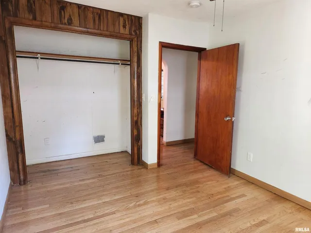 an empty room with wooden floor and a hallway