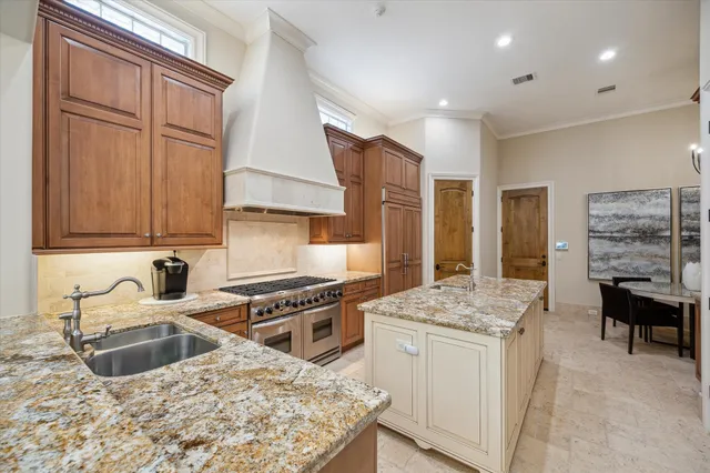 a kitchen with stainless steel appliances granite countertop a stove a sink dishwasher and a refrigerator with wooden cabinets