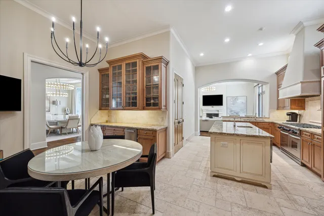 a kitchen with stainless steel appliances granite countertop a stove top oven a sink a dining table and chairs with wooden floor