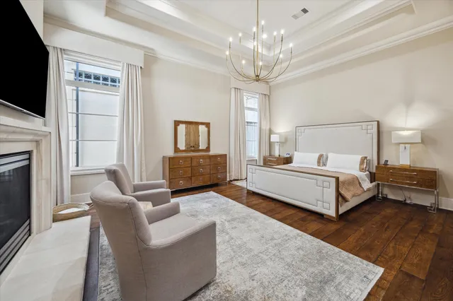 a spacious bedroom with a bed couch tv and wooden floor