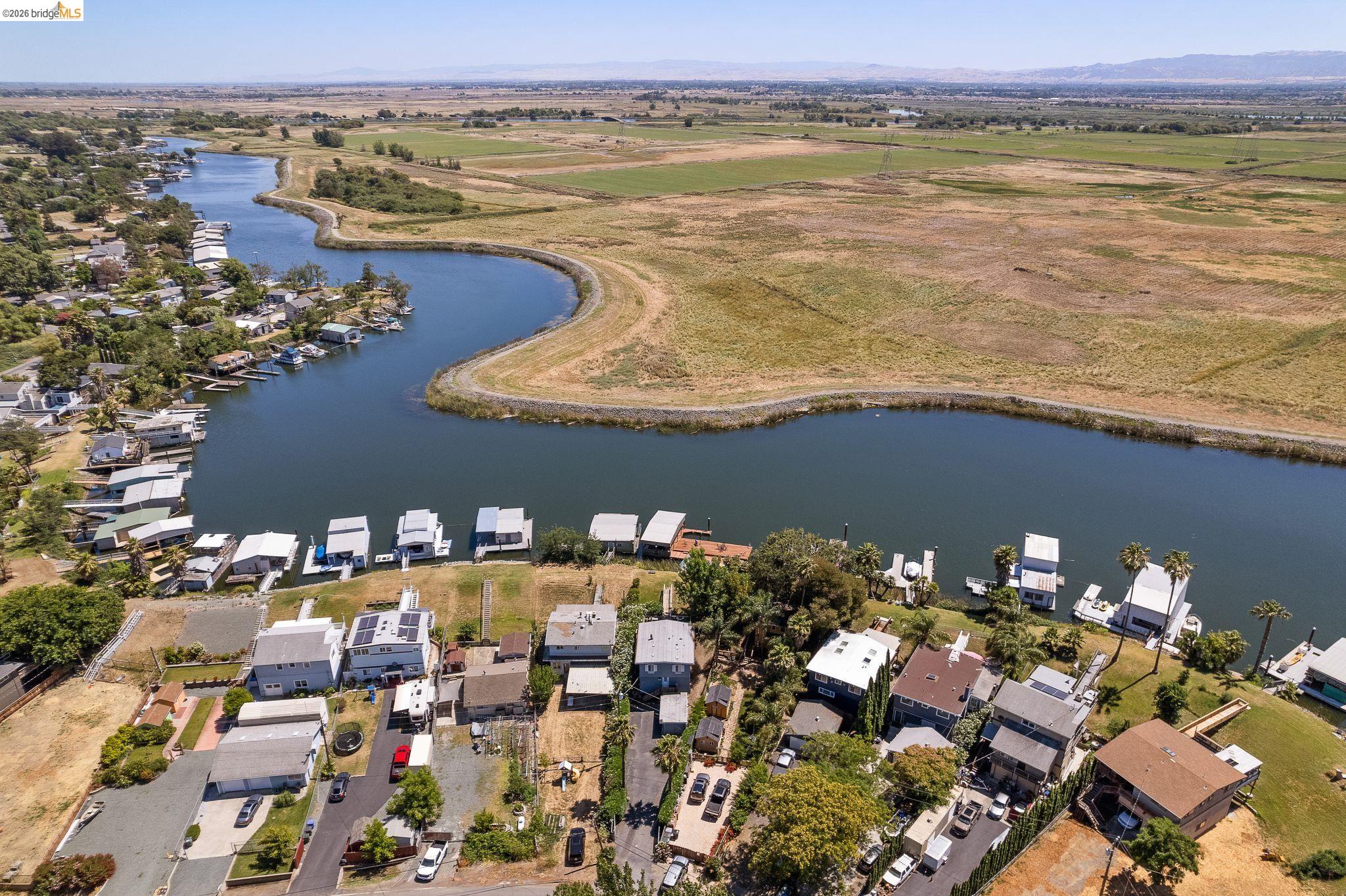 1704 Taylor Road Bethel Island, CA 94511 - Photo 72 of 73 Waterfront properties with private boat docks along a winding river, backed by expansive green and golden fields