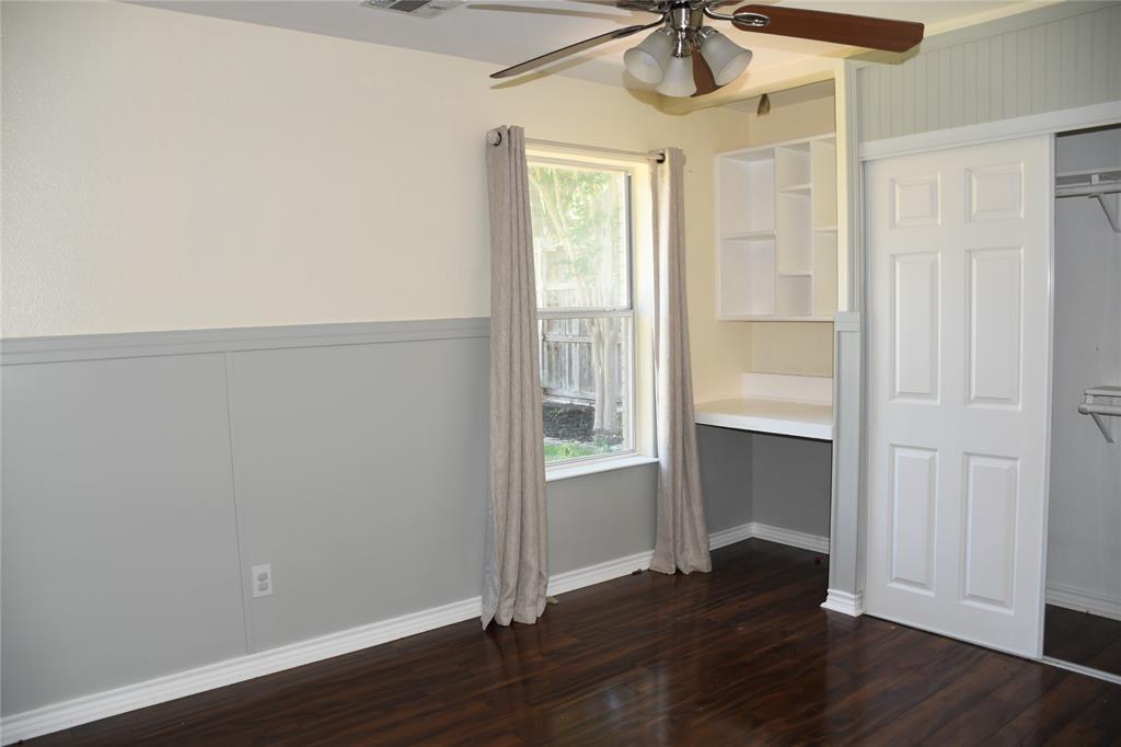 6241 Peach Tree Drive Midlothian, TX 76065 - Photo 11 of 19 Room featuring wood-finish flooring, two-tone walls with wainscoting, a ceiling fan, a built-in desk with shelving, and a sliding closet door