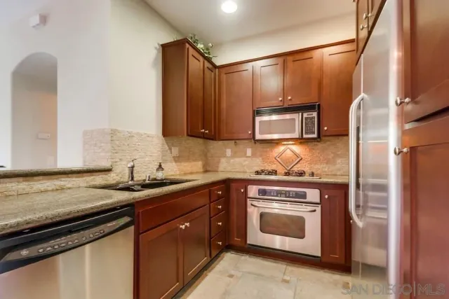 a kitchen with granite countertop a sink stove and microwave