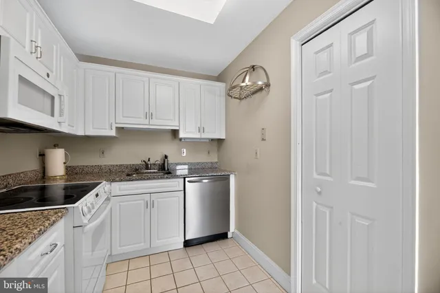 a kitchen with white cabinets and sink