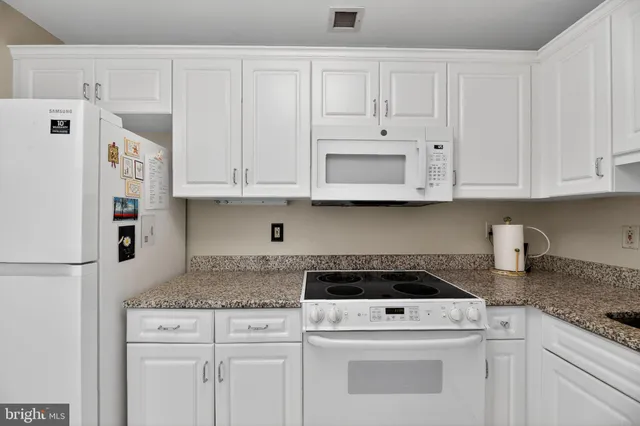 a kitchen with granite countertop white cabinets and white appliances