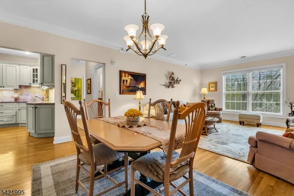 a dining room with wooden floor a chandelier a glass table and chairs