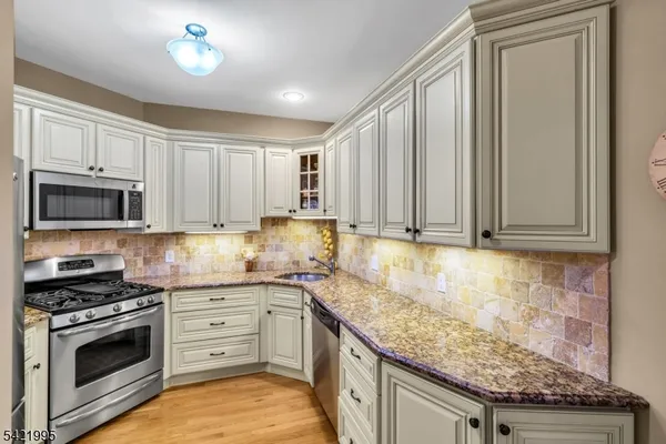 a kitchen with stainless steel appliances granite countertop a stove a sink and a microwave