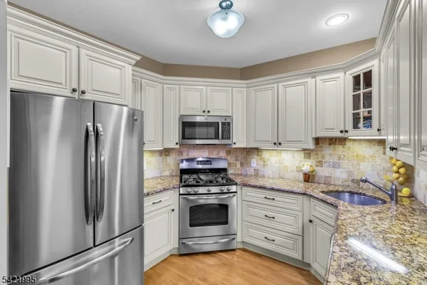 a kitchen with granite countertop a refrigerator stove and microwave