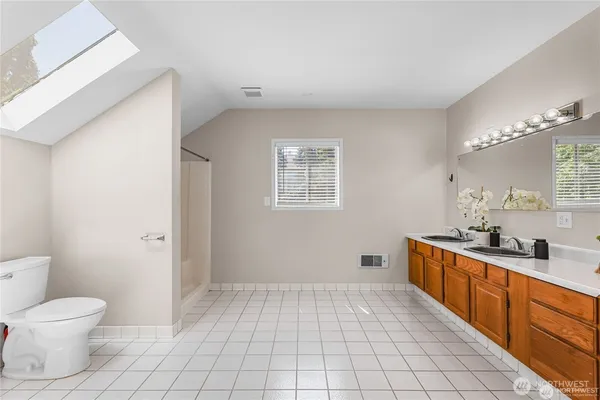 a spacious bathroom with a toilet a sink a mirror a lamp and vanity