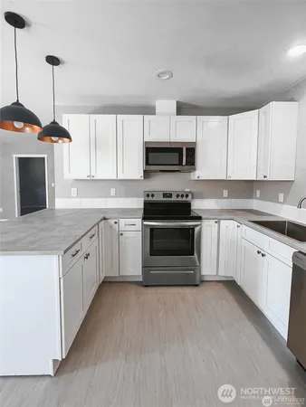 a kitchen with stainless steel appliances granite countertop a stove a sink and a microwave