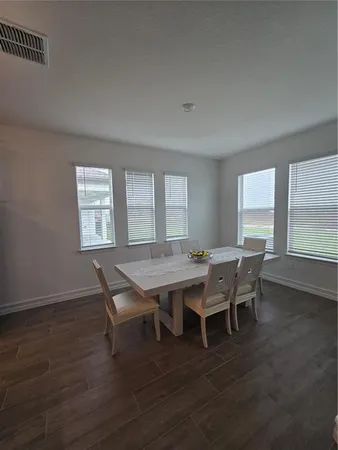 a dining room with wooden floor a chandelier a wooden table and chairs