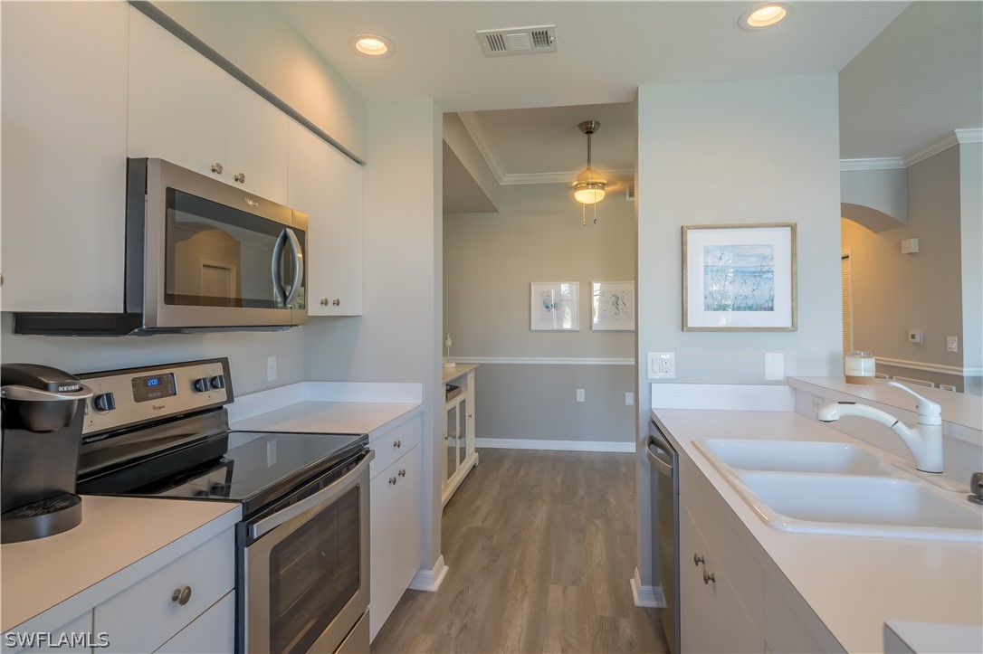 14101 Brant Point Circle, Unit 3203 Fort Myers, FL 33919 - Photo 7 of 34 a kitchen that has a sink a stove and wooden floor