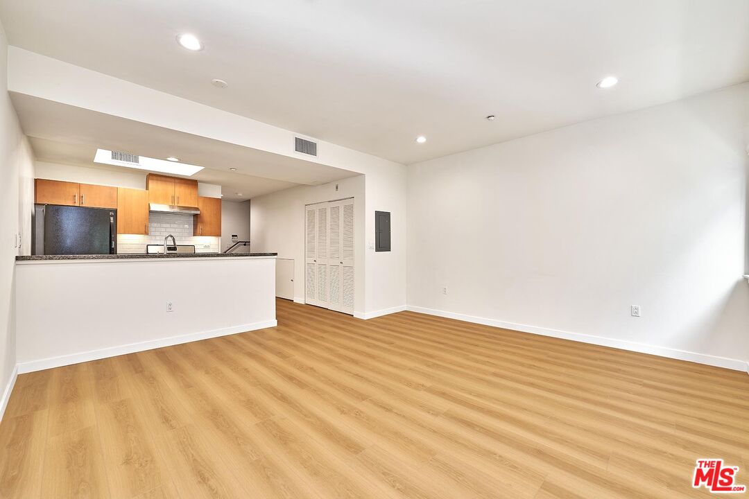 2864 Sunset Place, Unit 203 Los Angeles, CA 90005 - Photo 2 of 26 a view of a kitchen with kitchen island a sink wooden floor and a refrigerator