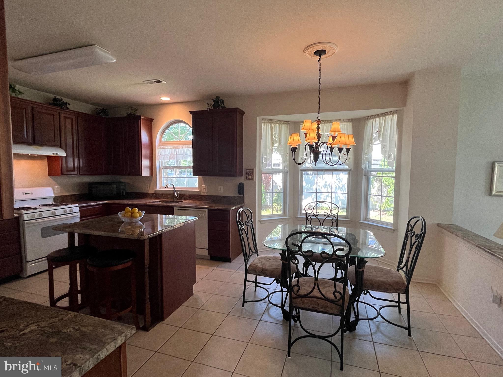 960 Butler Drive Williamstown, NJ 08094 - Photo 13 of 44 a kitchen with stainless steel appliances granite countertop a stove a sink dishwasher a dining table and chairs with wooden floor