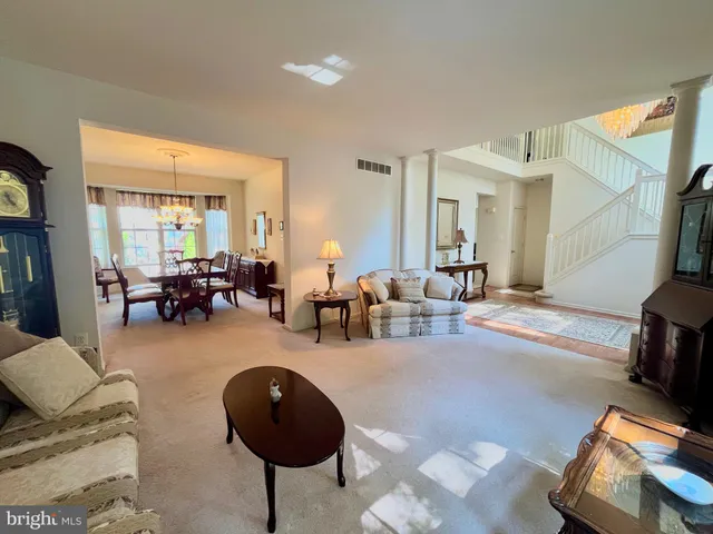 a living room with furniture and a large mirror next to a window