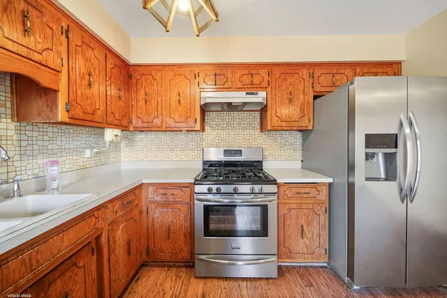 a kitchen with stainless steel appliances granite countertop a stove a sink and a refrigerator